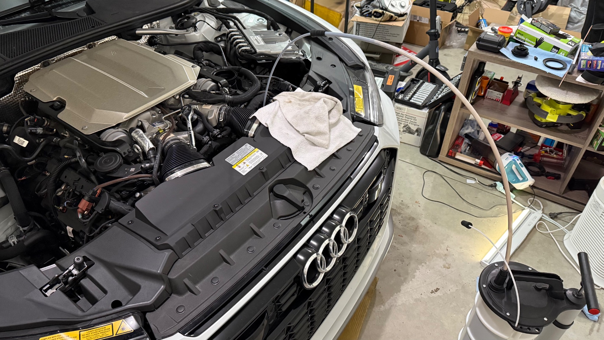 Audi RS6 engine bay during an oil change with a fluid extractor